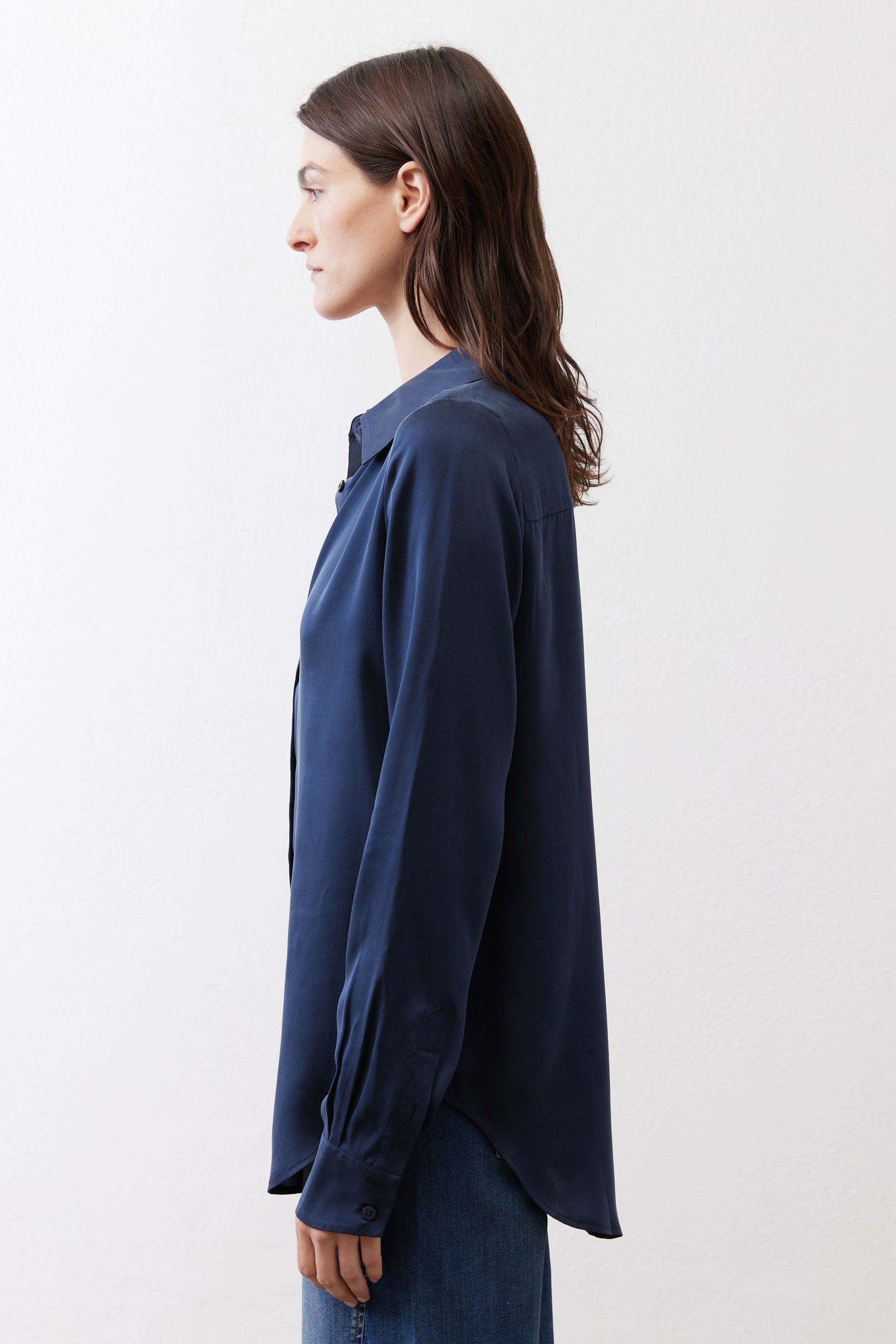 Dark blue silk button-down top side view with long sleeves and curved hem