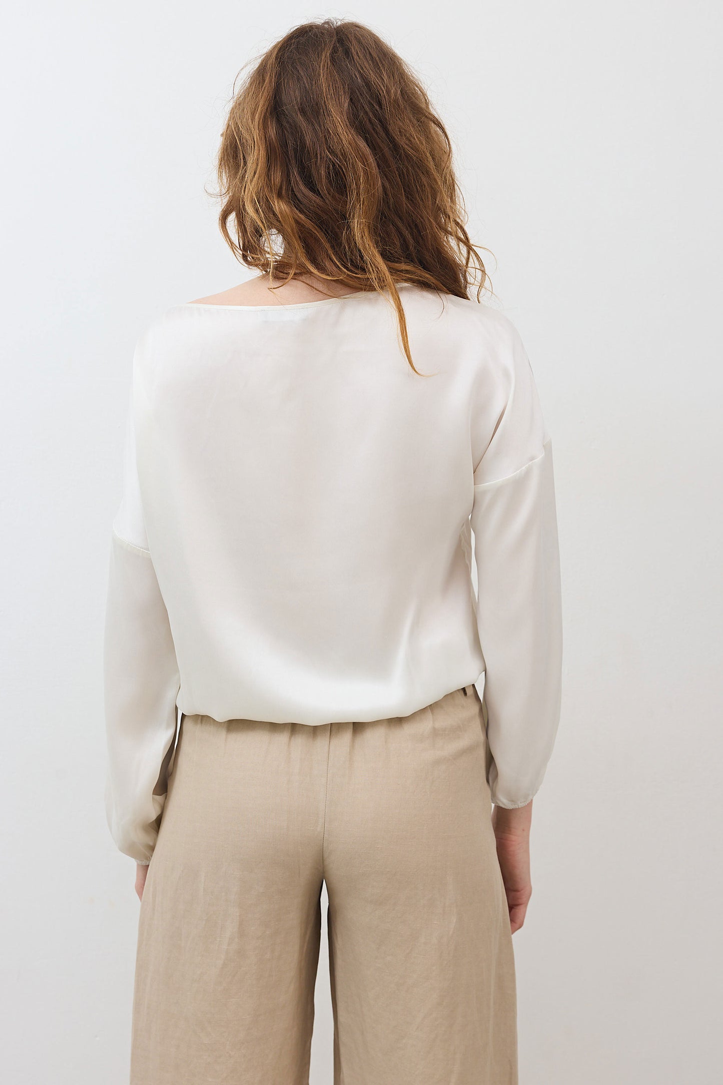 Ivory silk blouse with scoop back, long sleeves, and cinched hem