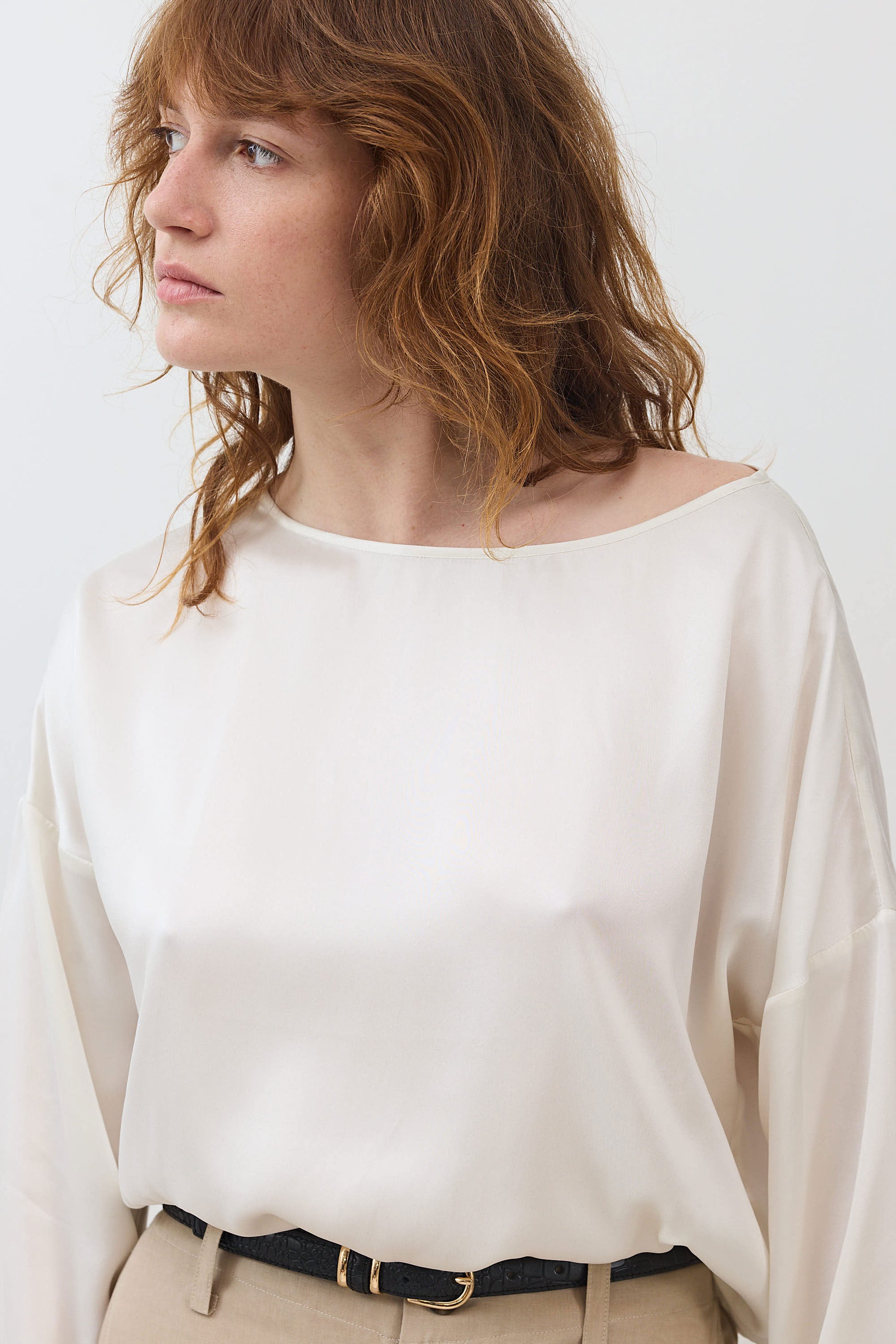 Ivory silk blouse with scoop neck and long puff sleeves; cinched hem