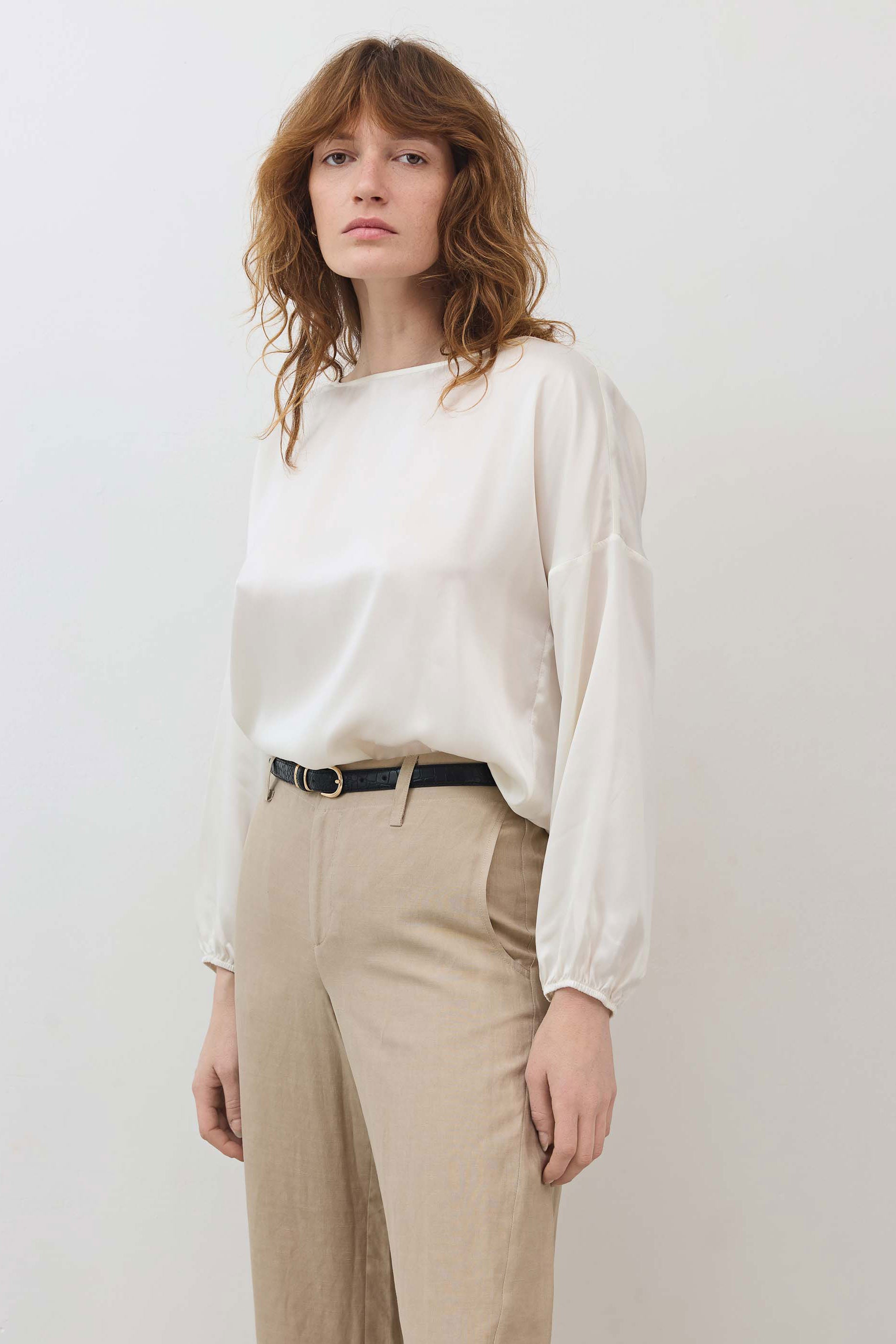 Ivory silk blouse with scoop neck and billowy long sleeves; cinched hem