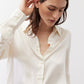 Ivory silk button-down top close-up with long sleeve cuff and button front