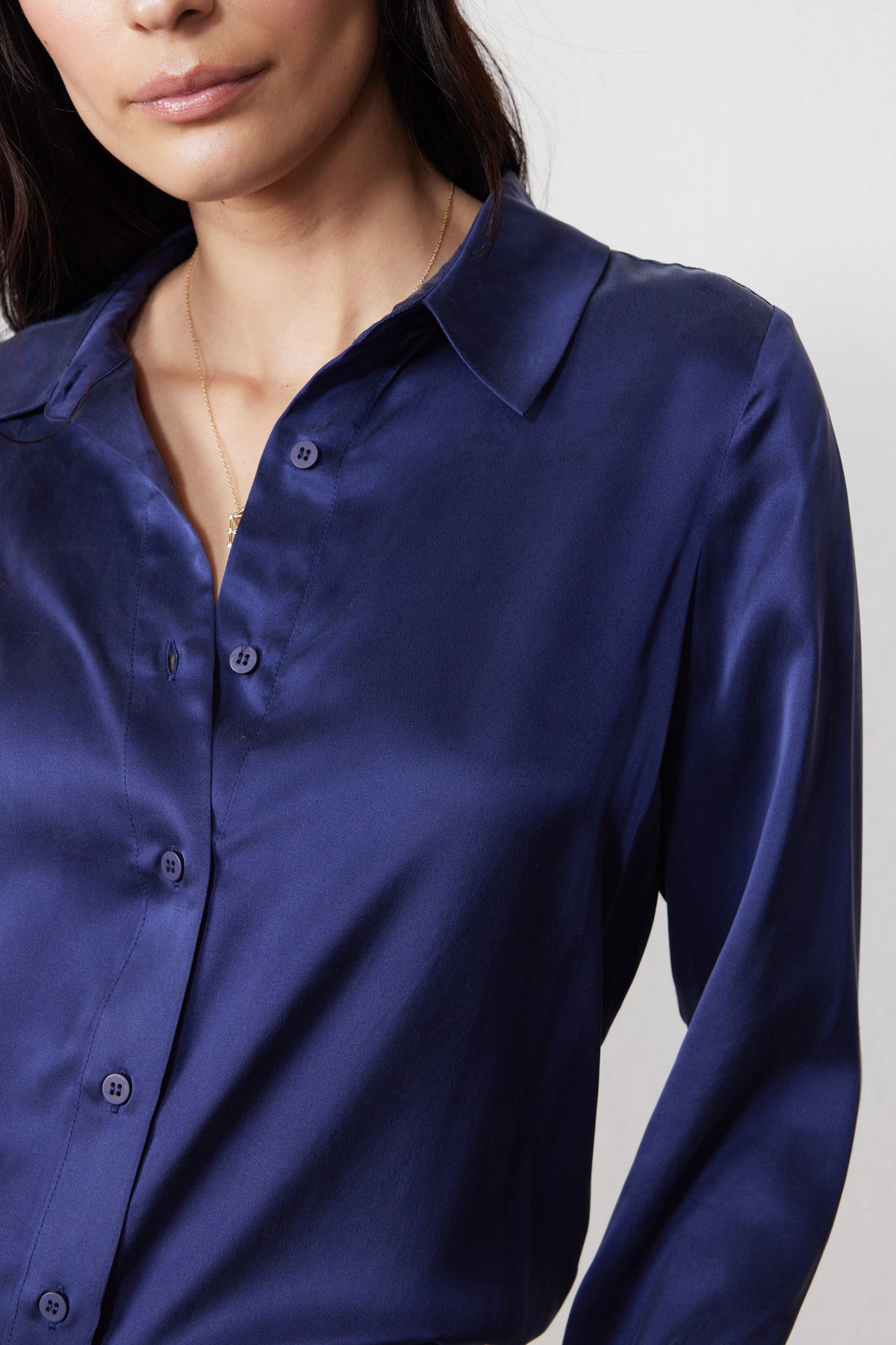 Close-up of the blue silk shirt's pointed collar, buttons, and smooth fabric.