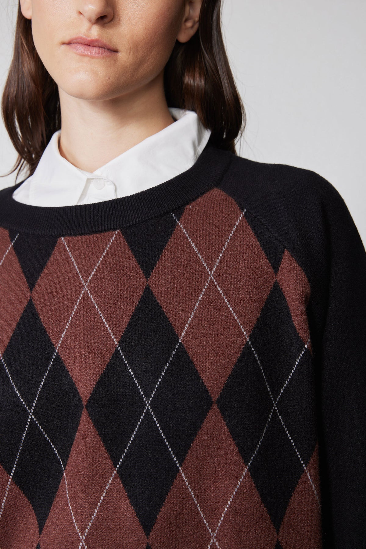 Neckline detail: black argyle sweater with rust diamond pattern and ribbed collar