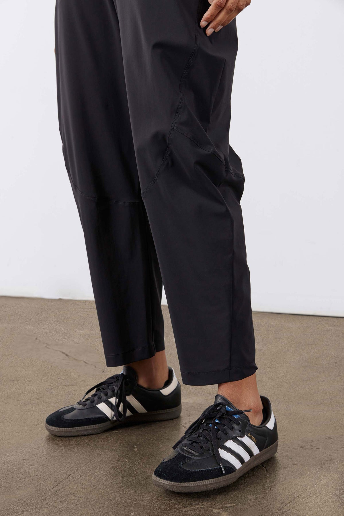 Black wide pants with cuffed hem and side pockets, worn with sneakers