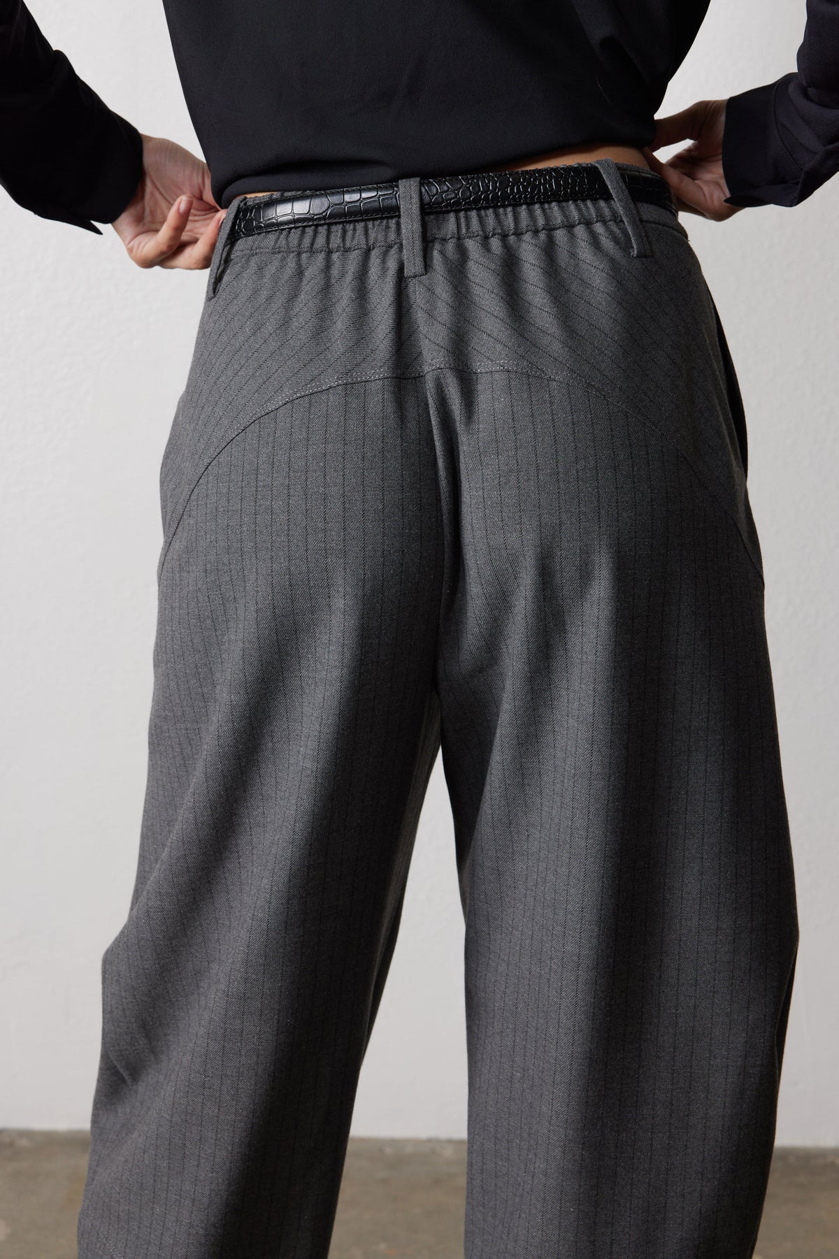 Gray pinstripe suit pants detail: back waistband, belt loops, and center pleats