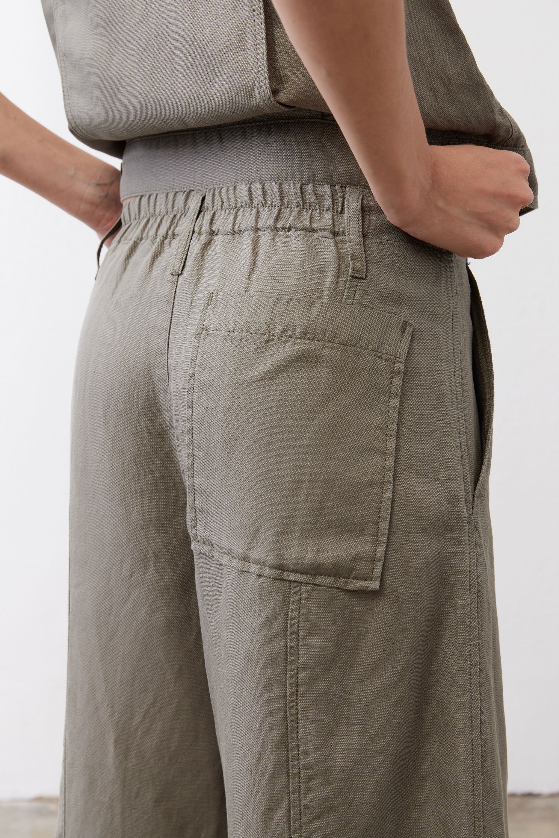 Olive pants detail: elastic waist, front patch pockets, and buttoned fly