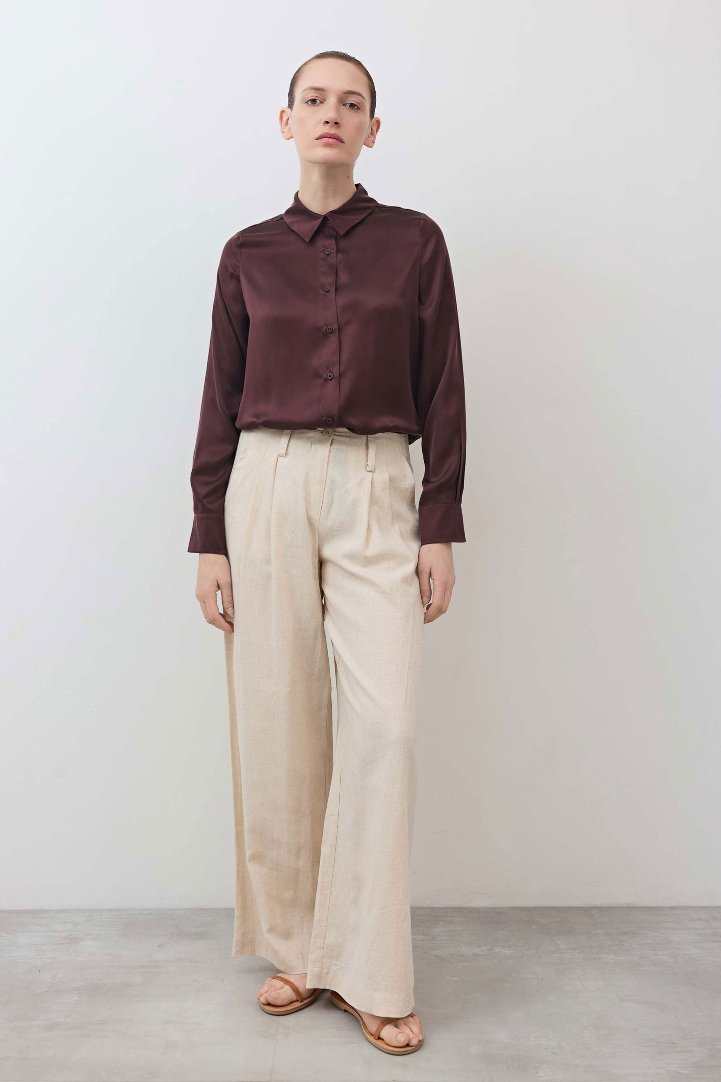 Oatmeal linen wide-leg trousers standing front view with tied waist and fluid wide legs