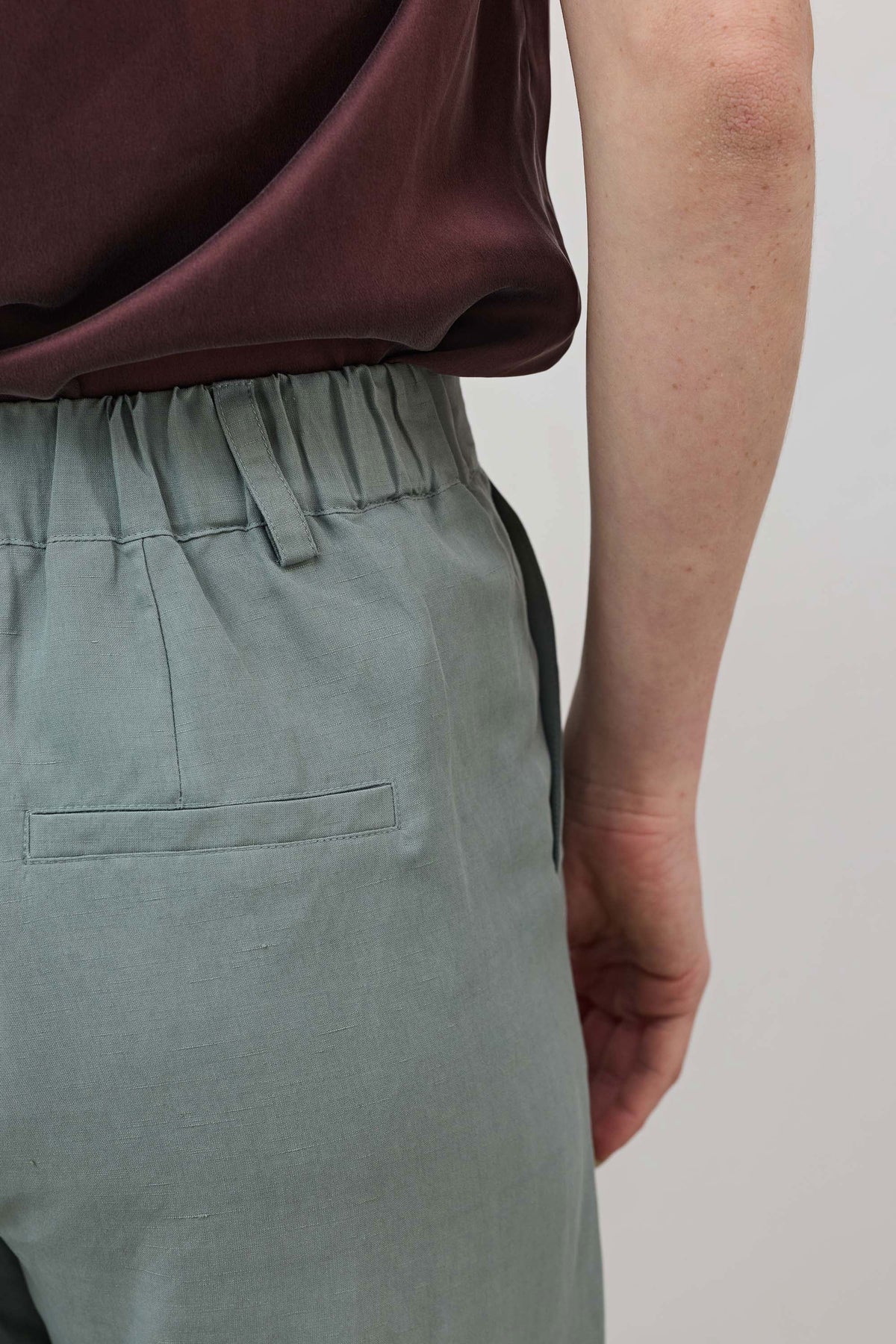 Chinois green belt-tied trousers with waistband pleats and front patch pocket