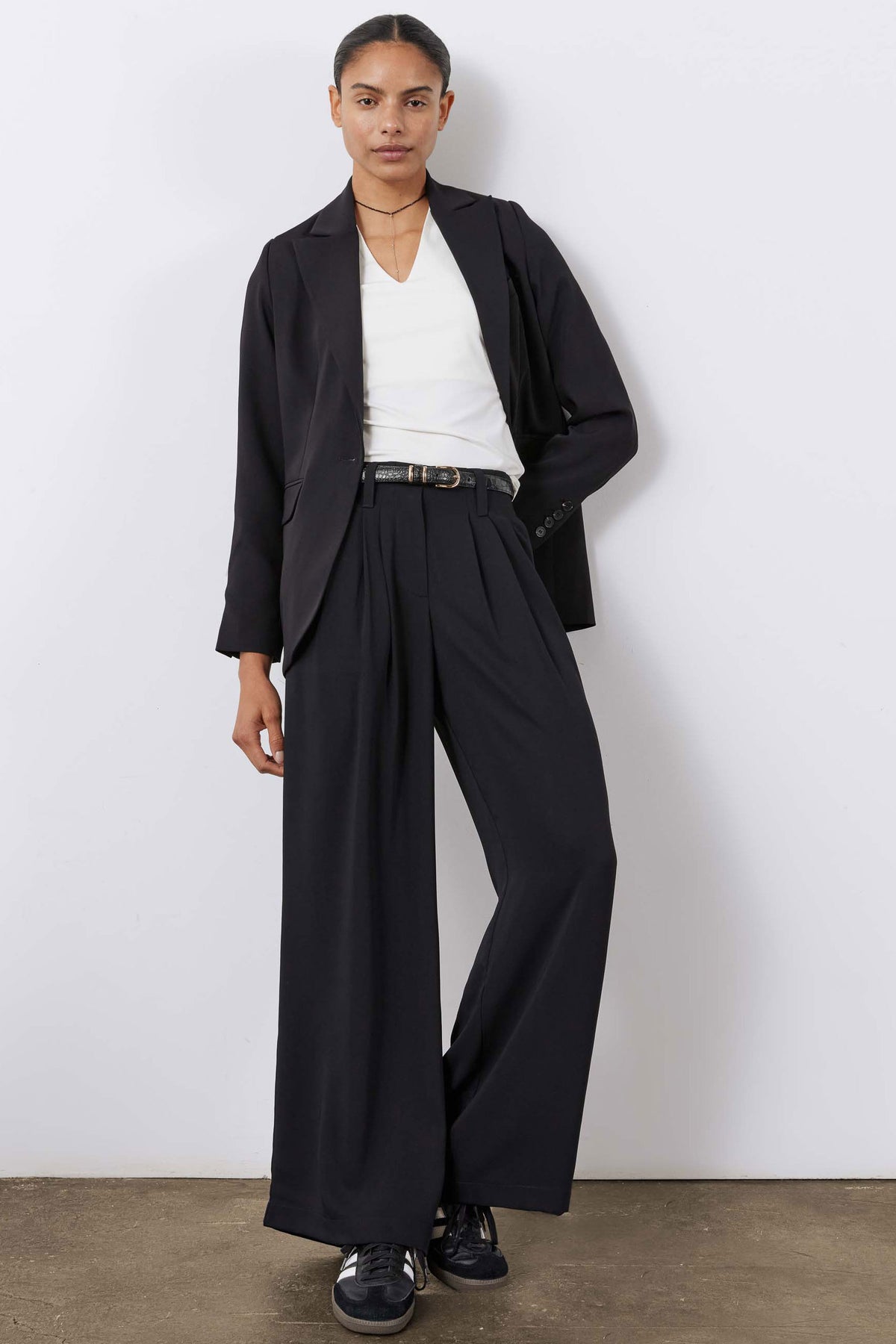 Black wide-leg trousers with pleated front, belt at waist, and long wide legs.