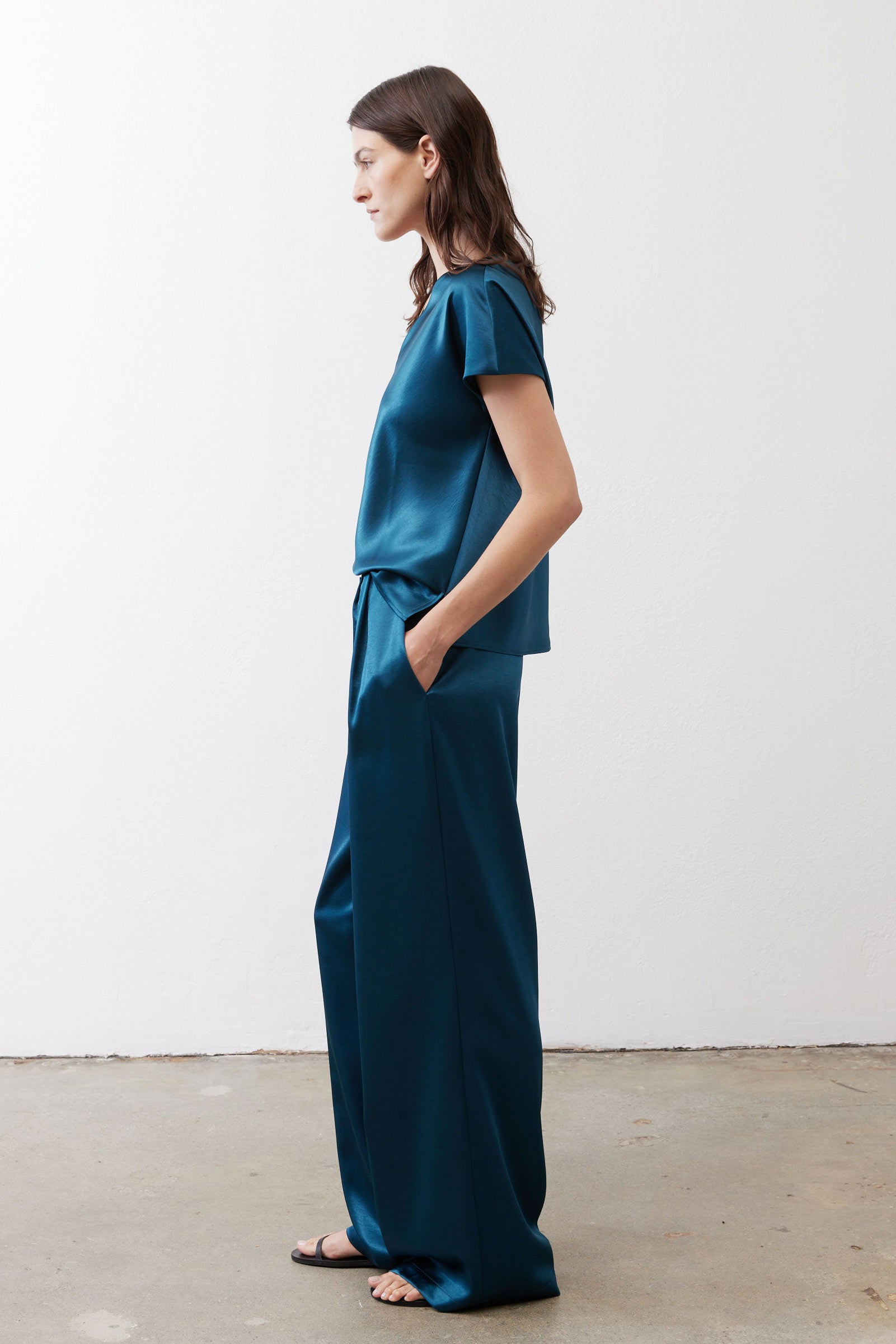 Deep teal wide-leg trousers with smooth front, belt loops, and tapered hem