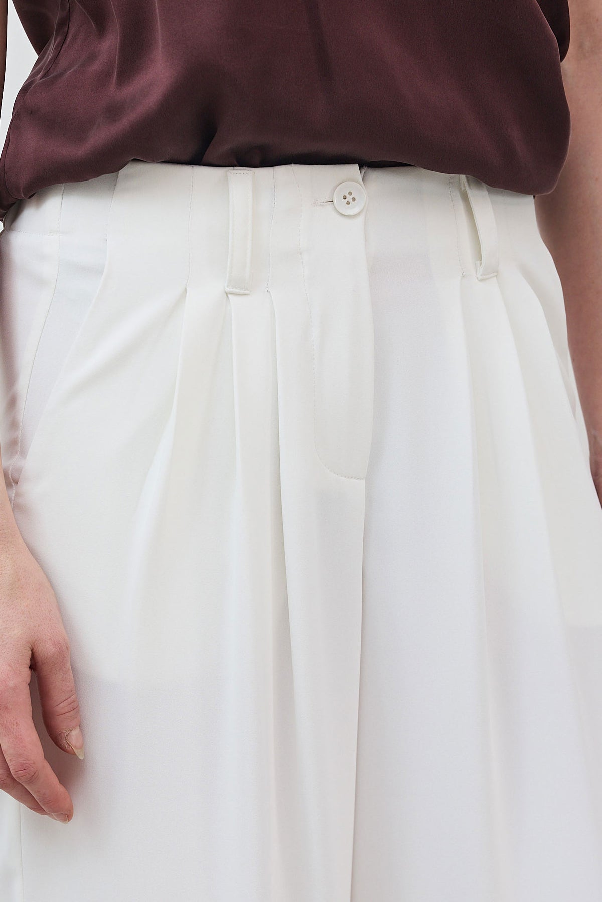White trousers waistband with pleats and small button closure