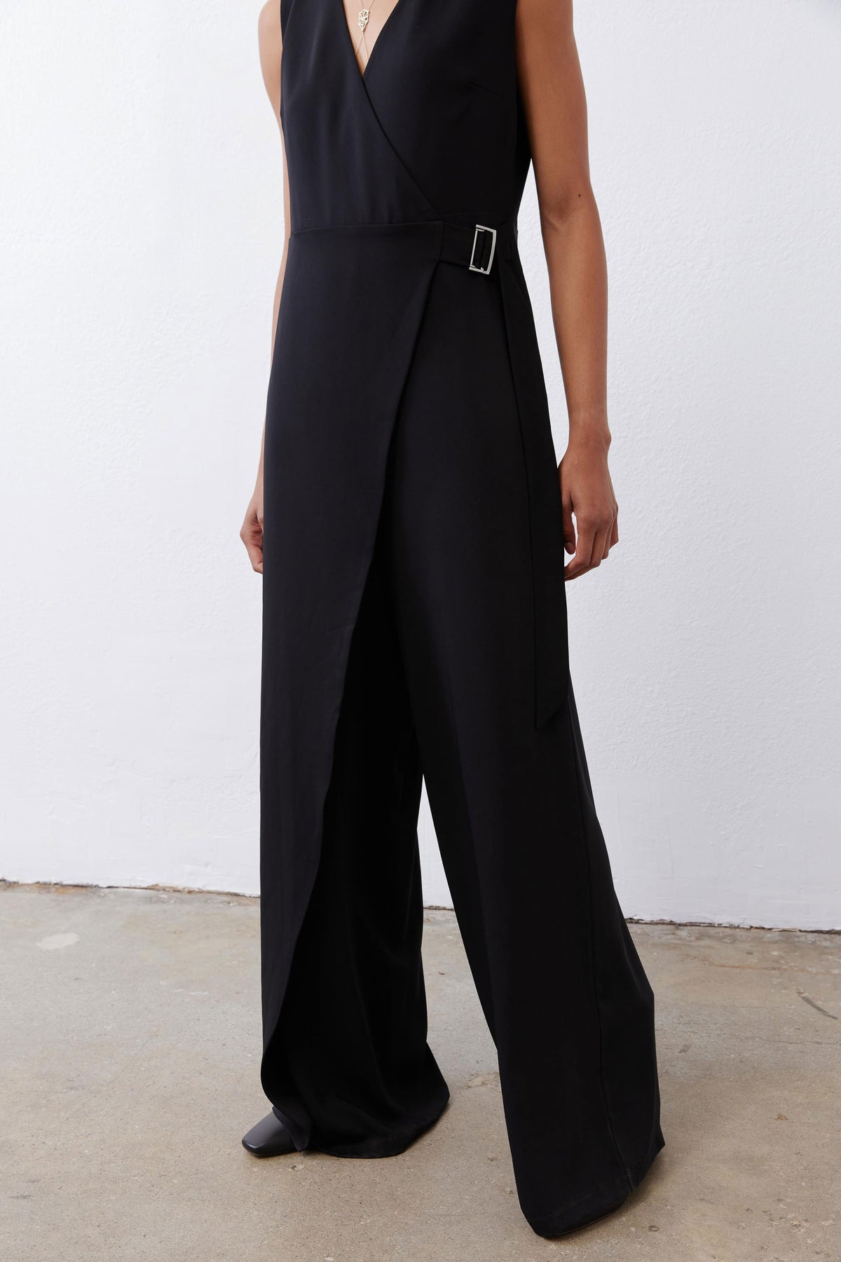 Black sleeveless wrap jumpsuit with V-neck and wide-leg pants with draped front