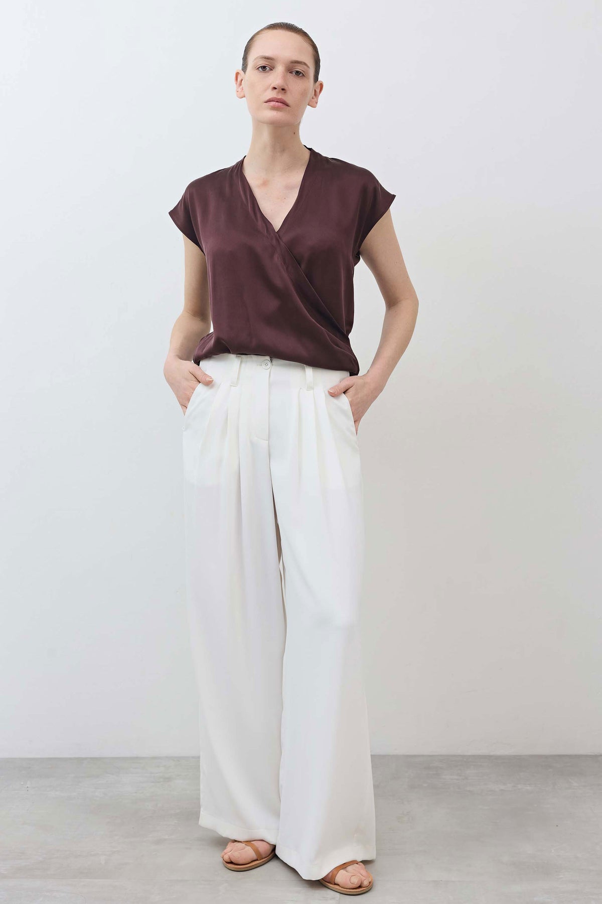 Wrap silk top in deep fudge brown with V-neck, draped front overlap; model front view.