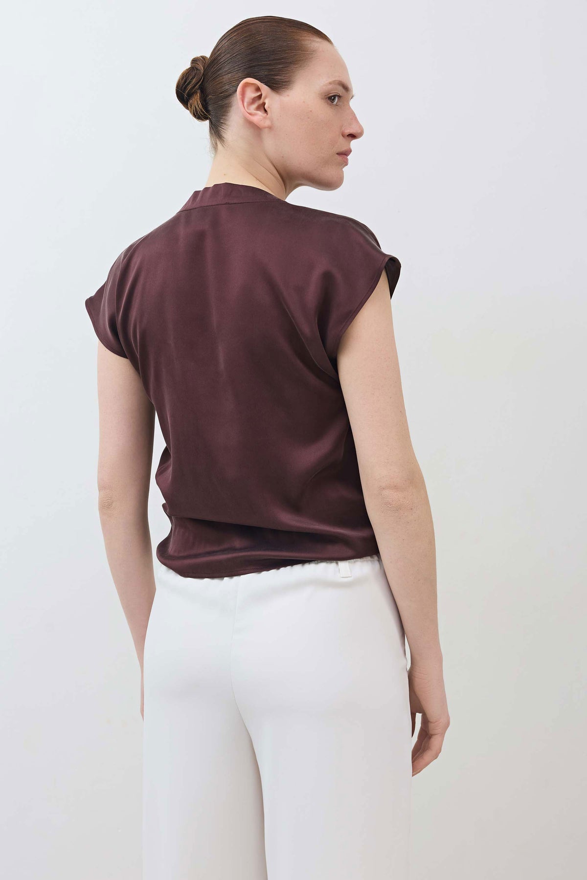 Back view of deep fudge brown wrap silk top with short sleeves and tied drape at waist.