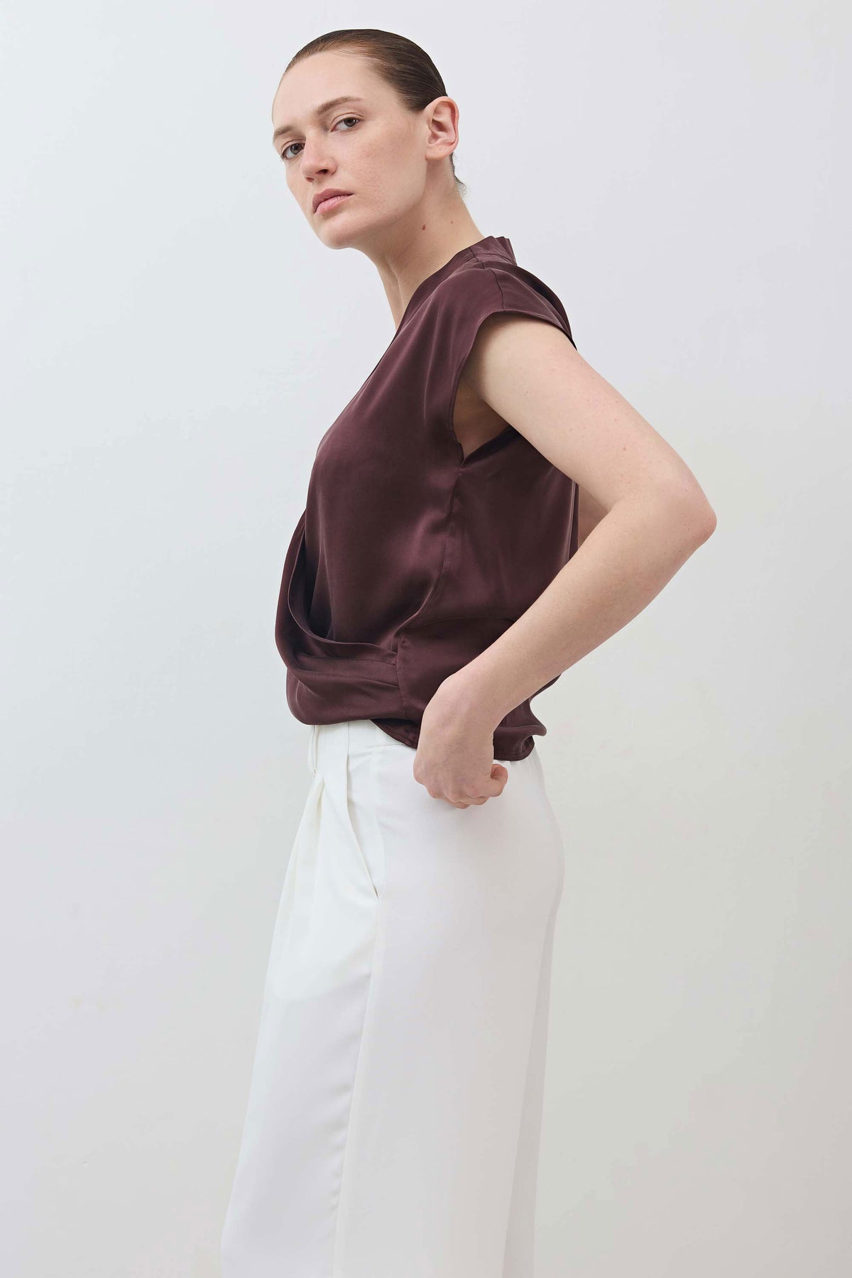 Fudge brown wrap silk top with V-neck and short sleeves, draped wrap front; side pose.