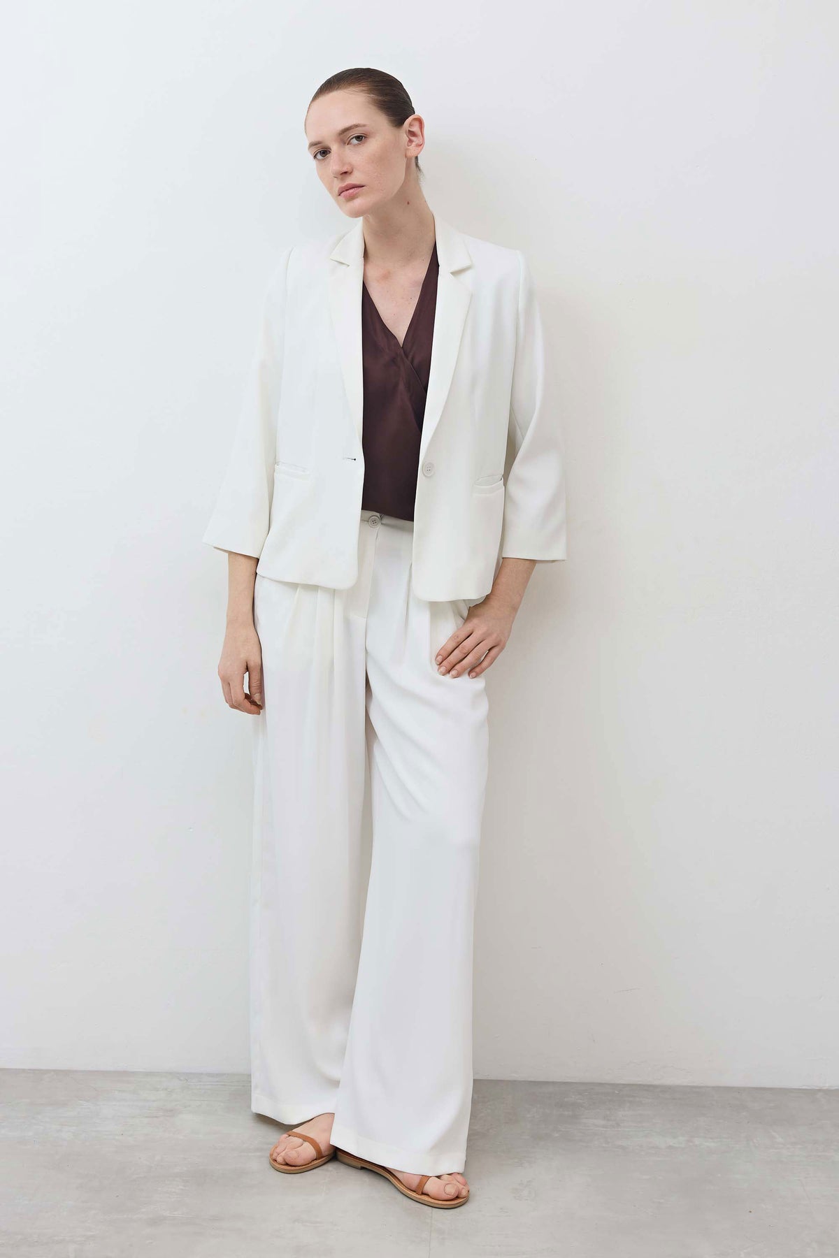 Fudge brown wrap silk top layered under a white jacket, with V-neck draped front.