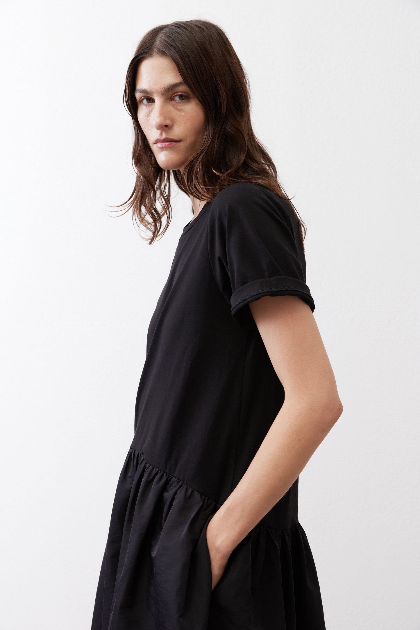 Black short-sleeve crewneck dress with gathered skirt, side profile view
